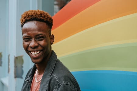 positive young black person laughing in front of pride flag