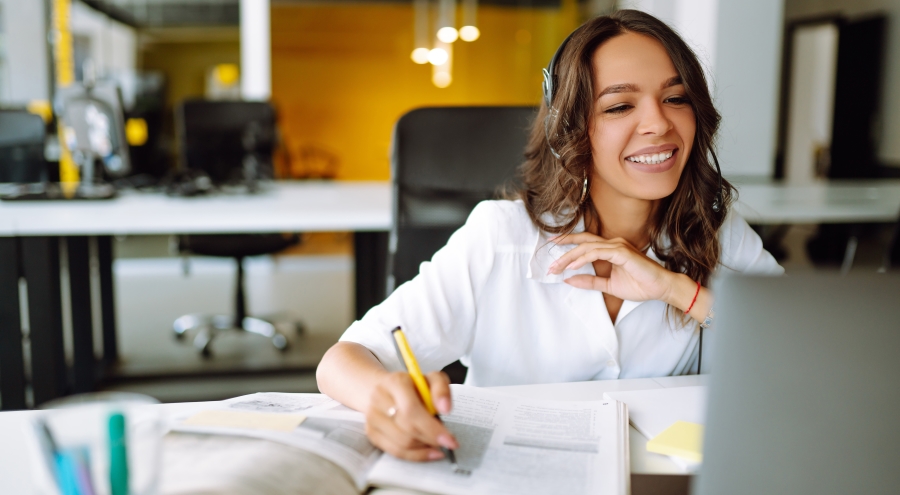 woman wearing headset sitting at desk looking at computer screen